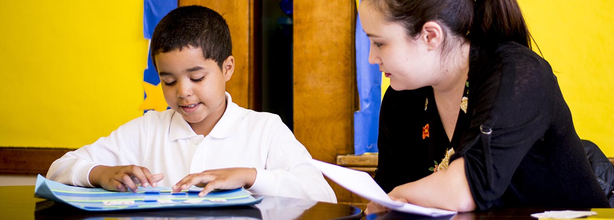 A teacher works with a student during a reading lesson in class.