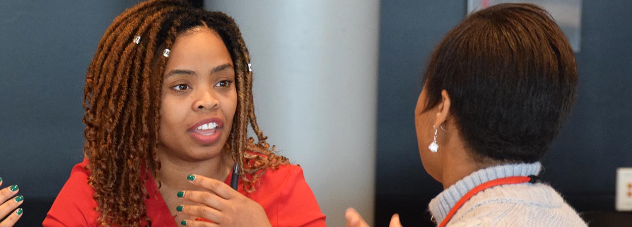 Two attendees in discussion during a break at the 2020 School of Education Research Colloquium.