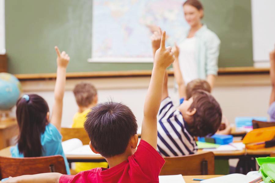 Children raise their hands in a Geography class.